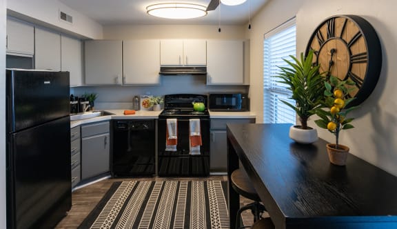 a kitchen with white cabinets and a black and white rug