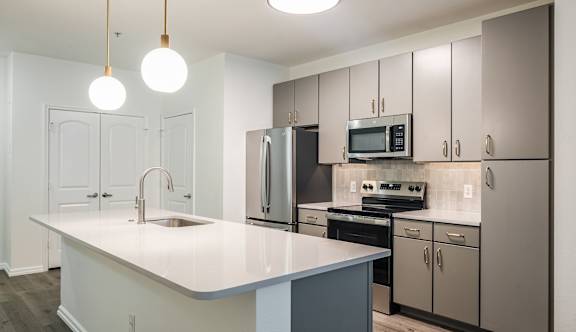 A kitchen with a white countertop and grey cabinets.