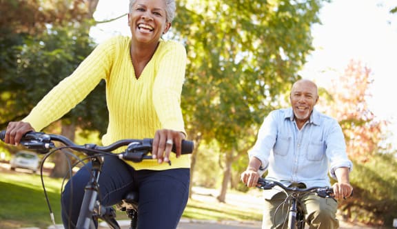 an older couple riding bikes in a park