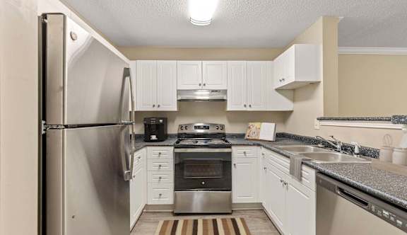 A kitchen with a stainless steel refrigerator and white cabinets.