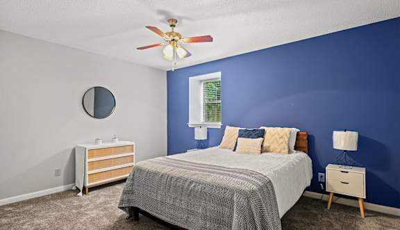 A bedroom with a bed, dresser, and mirror.