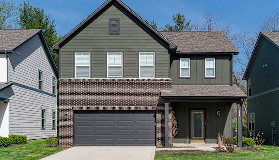 A house with a grey garage door is in front of two other houses.