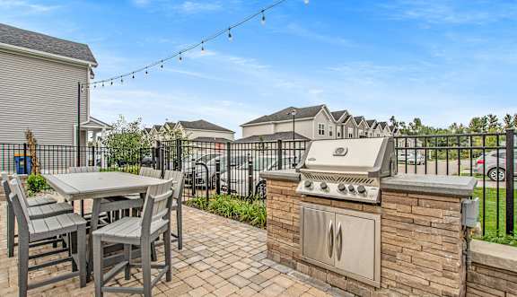A patio with a table, chairs and a grill.