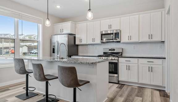 a kitchen with white cabinets and a bar with two chairs