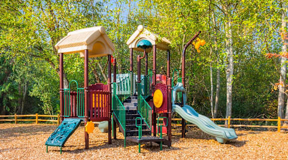 A playground with a green slide and a red and yellow structure.
