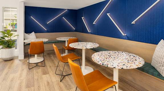 A blue wall with neon lights and a table with chairs in front of it.