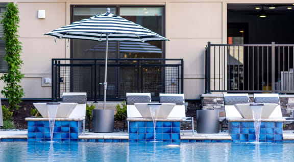 a hotel pool with white chairs and an umbrella