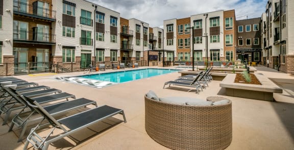 an outdoor pool with lounge chairs at an apartment building