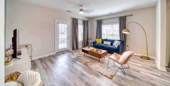 A living room with a blue couch and a wooden floor.