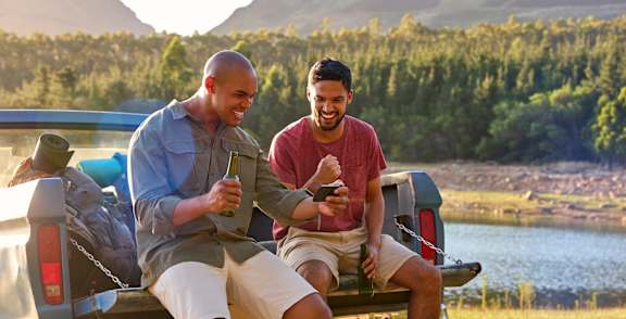 Men Sitting on Tailgate Smiling and Looking at Phone