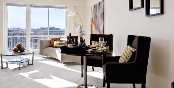 A living room with a table and chairs and a view of the city.