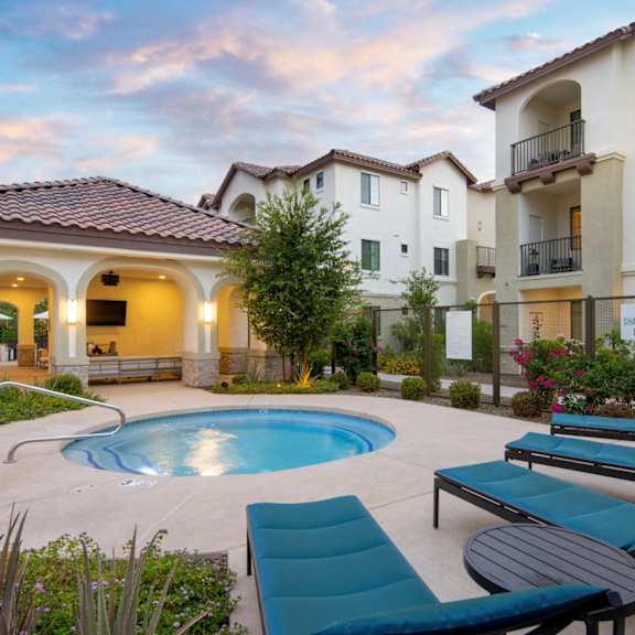 A pool surrounded by lounge chairs and a building in the background.