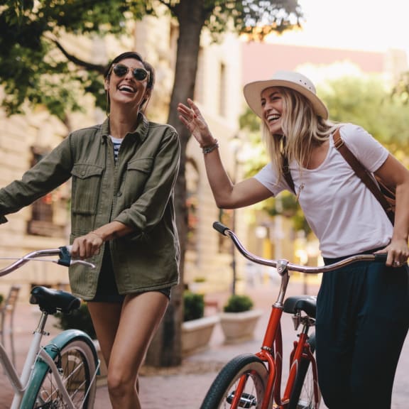 Friends Laughing Together while Walking with Bikes