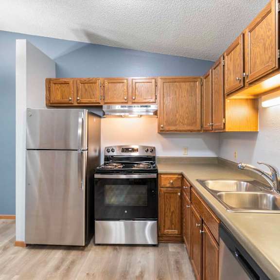 A kitchen with a stainless steel refrigerator, oven, and sink.