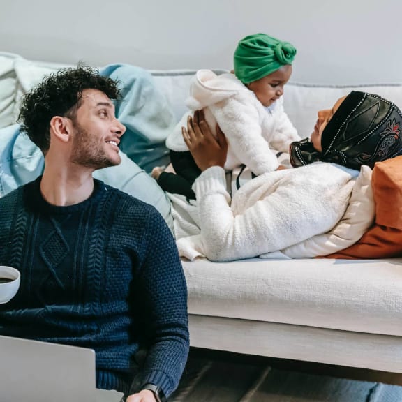 a man sitting on a couch with a cup of coffee and a laptop