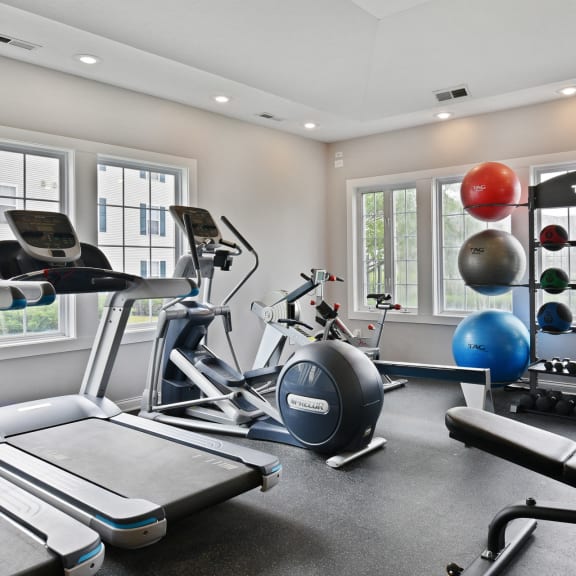 a gym with treadmills and other exercise equipment and windows