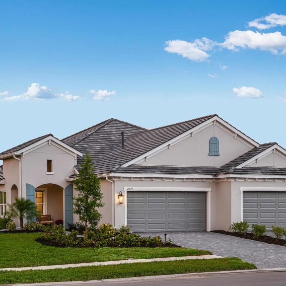 a pale house with a lawn and small trees. at Marisol, Bradenton, FL