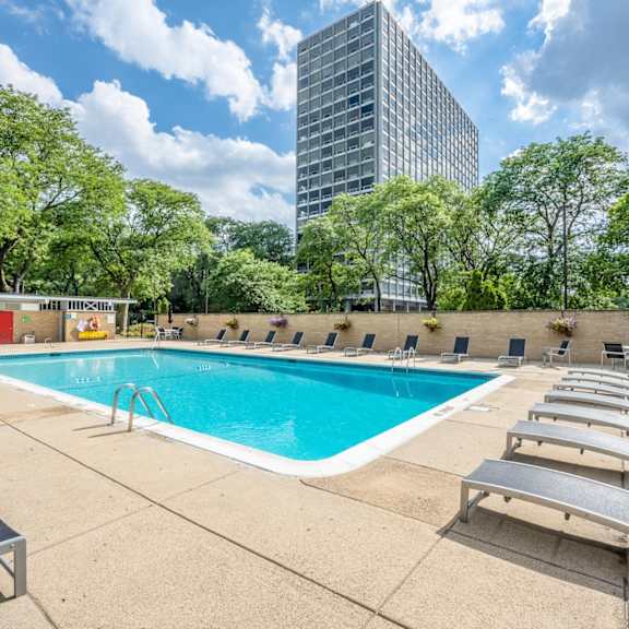 A swimming pool surrounded by trees and buildings in the background.