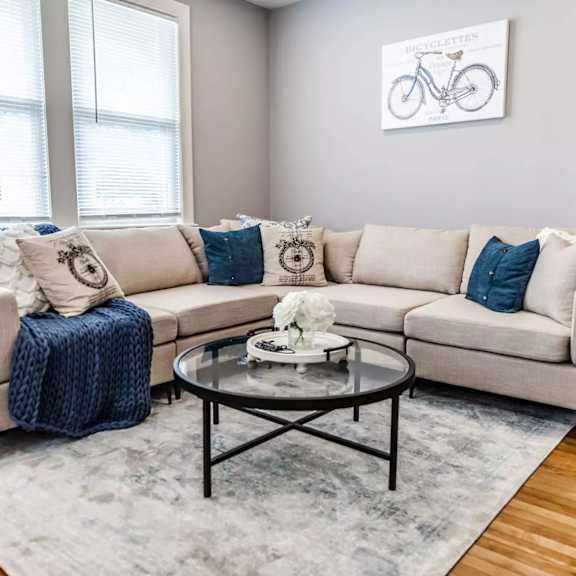 A living room with a beige couch, a coffee table, and a bicycle picture on the wall.