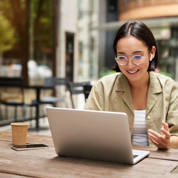 Woman Sitting at Table Smiling while Working on Laptop
