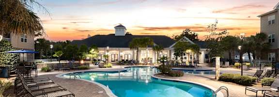 a swimming pool at sunset with a building in the background