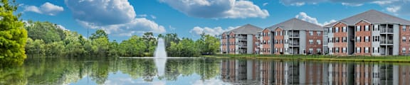 A serene lake with a building in the background and clouds in the sky.