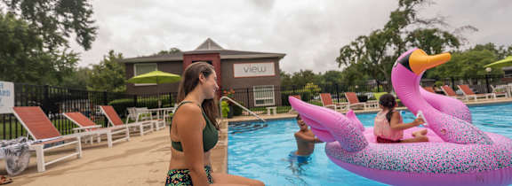 a woman sits on the edge of a swimming pool with her legs in the water