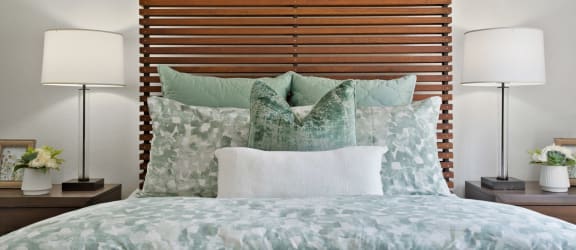 a bedroom with a bed and pillows and a wooden headboard