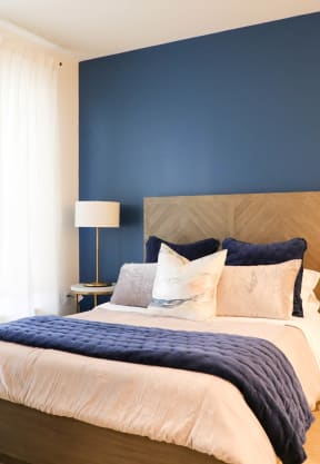 a bedroom with a blue accent wall and a bed with a wooden headboard
