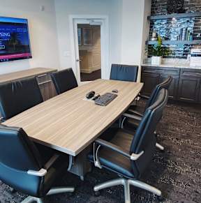 a conference room with a desk and chairs and a mirror