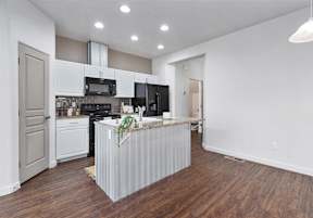 A kitchen with a white counter and wooden floors at Verraso Village Townhomes in Meridian, 83646