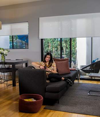 a woman sits on a couch in a living room  at 888 Hilgard – Furnished Apartments, Los Angeles, CA