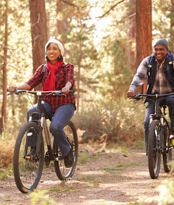 Man and Woman Riding Bikes Through Woods Together