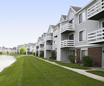 a row of townhomes with balconies overlooking a pond