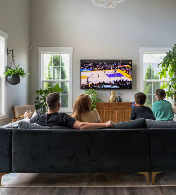 a family sitting on a couch in a living room watching a basketball game on the tv
