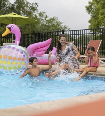 a woman and two children splashing in a swimming pool