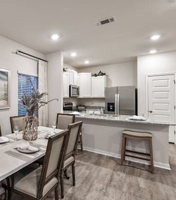 a dining area with a table and chairs and a kitchen in the background