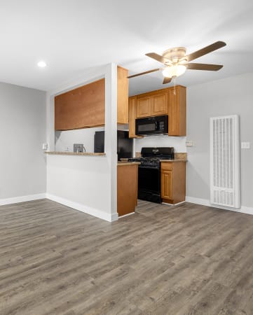a living room with a ceiling fan and a kitchen in the background