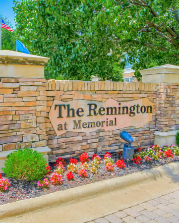 The Remington at Memorial property sign at the community entrance. Surrounded by beautiful lush greenery and flowers.