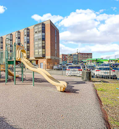 A playground with a yellow slide in front of a building at Fullerton Court Apartments, Illinois