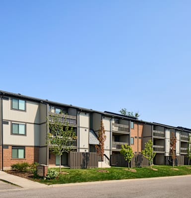 Apartment building with a grey facade and a green lawn in front.