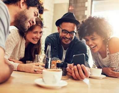 a group of people sitting at a table looking at a cell phone
