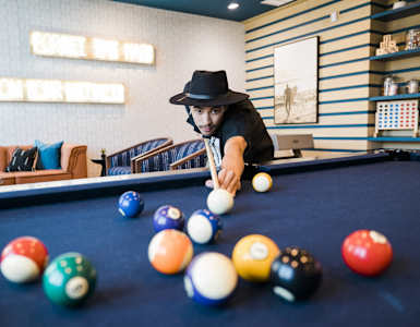 A man in a hat is playing pool.