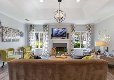 A living room with a brown couch and a chandelier.