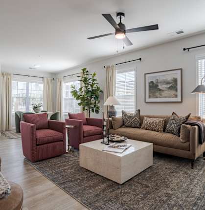 A living room with a red chair and a brown couch.