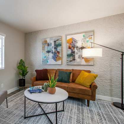 a living room with a brown couch and two paintings on the wall at Ascent 1829, Phoenix