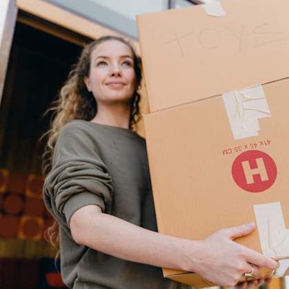 a woman holding a cardboard box with a red h logo on it