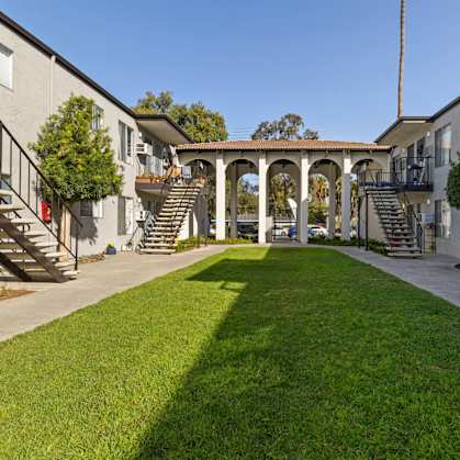 A courtyard with a grassy area and a building on either side.
