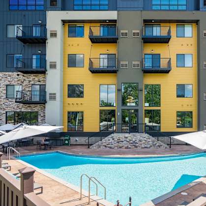 a swimming pool at an apartment building with a pool and umbrellas. Circle Pines, MN Lexington Lofts
