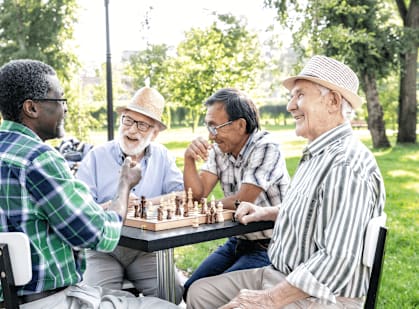 Four men playing chess in a park.